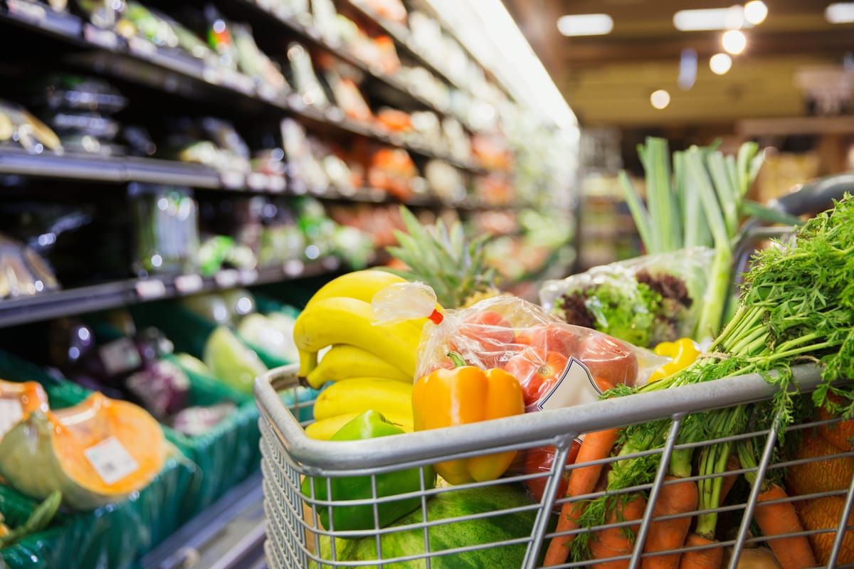 Einkaufswagen mit frischem Obst und Gemüse im Supermarkt