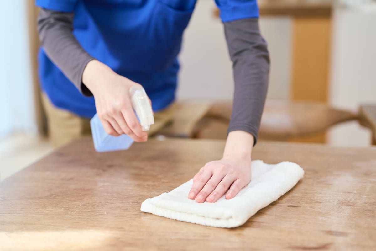 Betreuungskraft von Helfen mit Herz reinigt einen Tisch im Wohnbereich